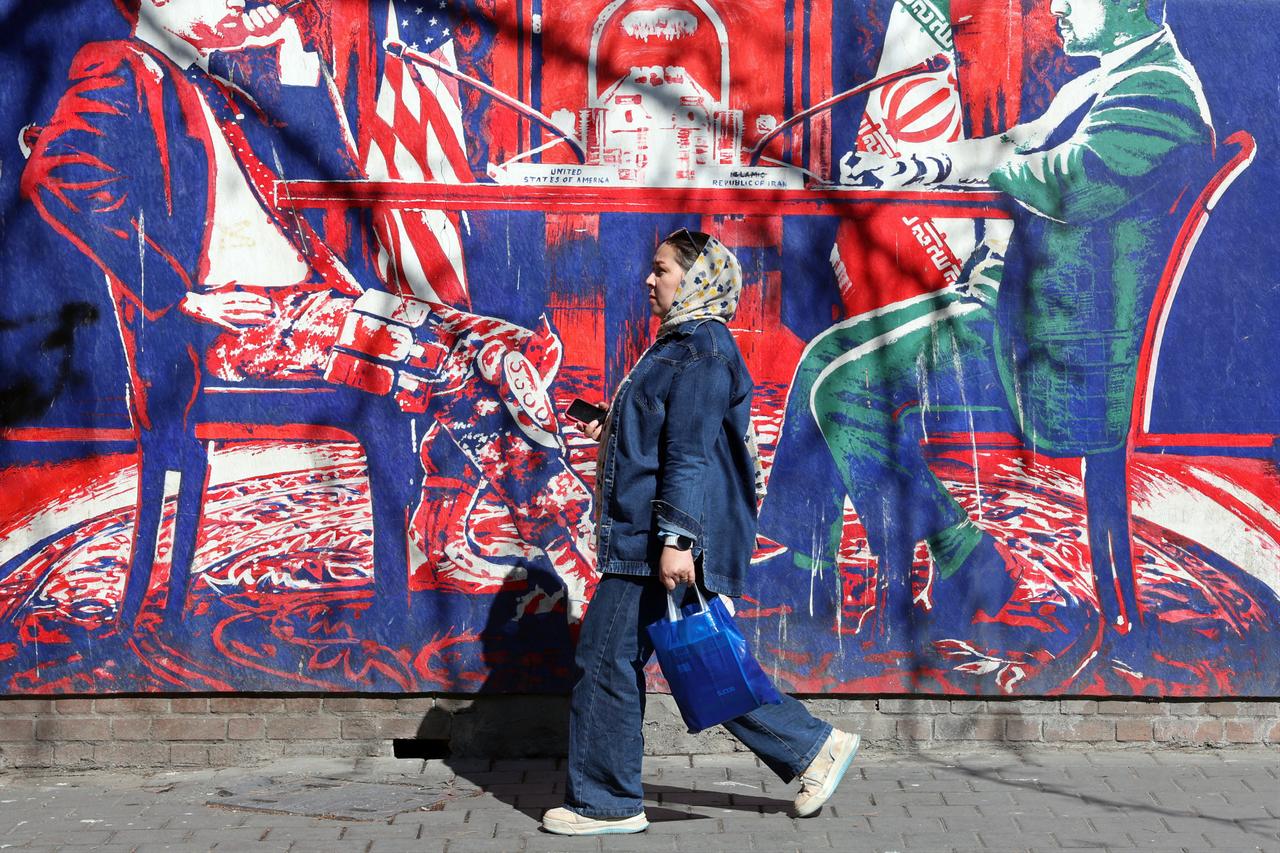 An Iranian woman walks past an anti-US mural featuring Iran-US talks, next to the former US embassy in Tehran, Iran, Feb. 26, 2026. (AFP Photo)