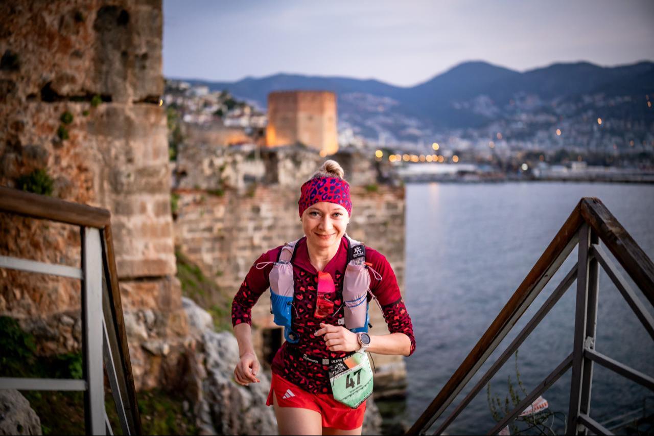 A female athlete runs along the historic walls overlooking the Mediterranean, with Alanya’s iconic Red Tower in the background, highlighting the race’s blend of history and endurance, Alanya, Türkiye. (Photo via Alanya Ultra Trail)