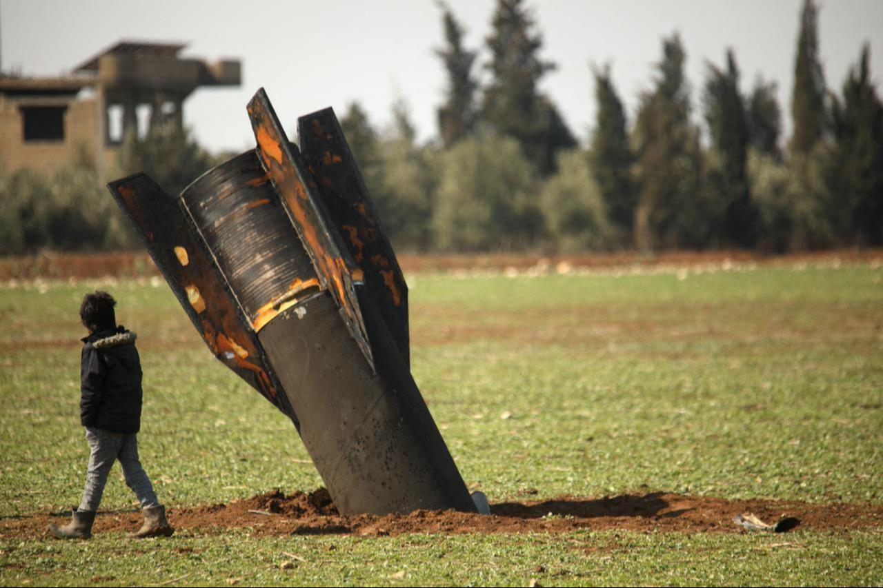A boy walks past an unexploded missile that landed in an open field on the outskirts of Qamishli, eastern Syria, on March 5, 2026. (AFP Photo)
