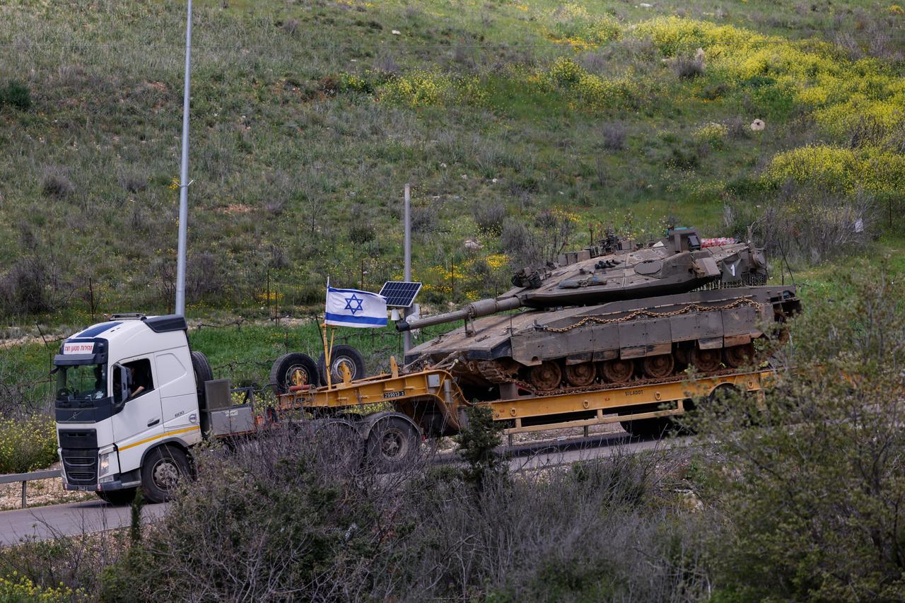 An Israeli military truck carries a tank in the Upper Galilee region of northern Israel, near the border with Lebanon on March 31, 2026. (AFP Photo)