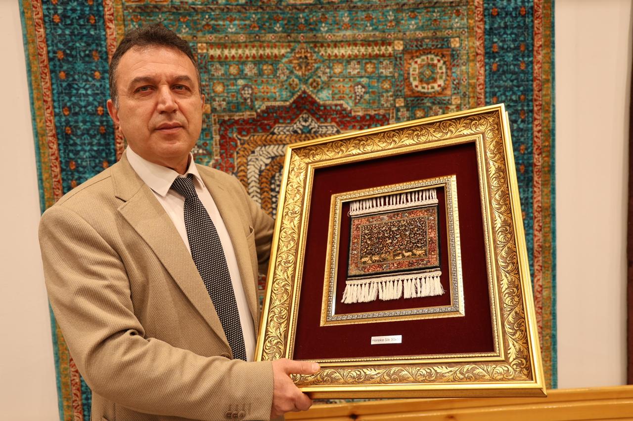 Carpet expert Hakan Demiratan holds the finely woven silk carpet featuring 2,500 double knots per square centimeter at a carpet showroom in Cappadocia, Türkiye, March 3, 2026. (IHA Photo)