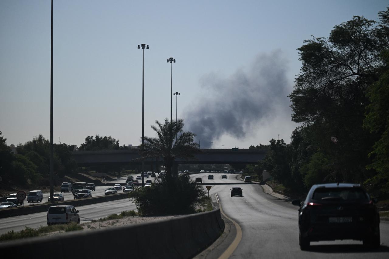 Motorists drive along a street as smoke rises from a reported Iranian strike in the area where the US Embassy is located in Kuwait City on March 2, 2026. (AFP Photo)