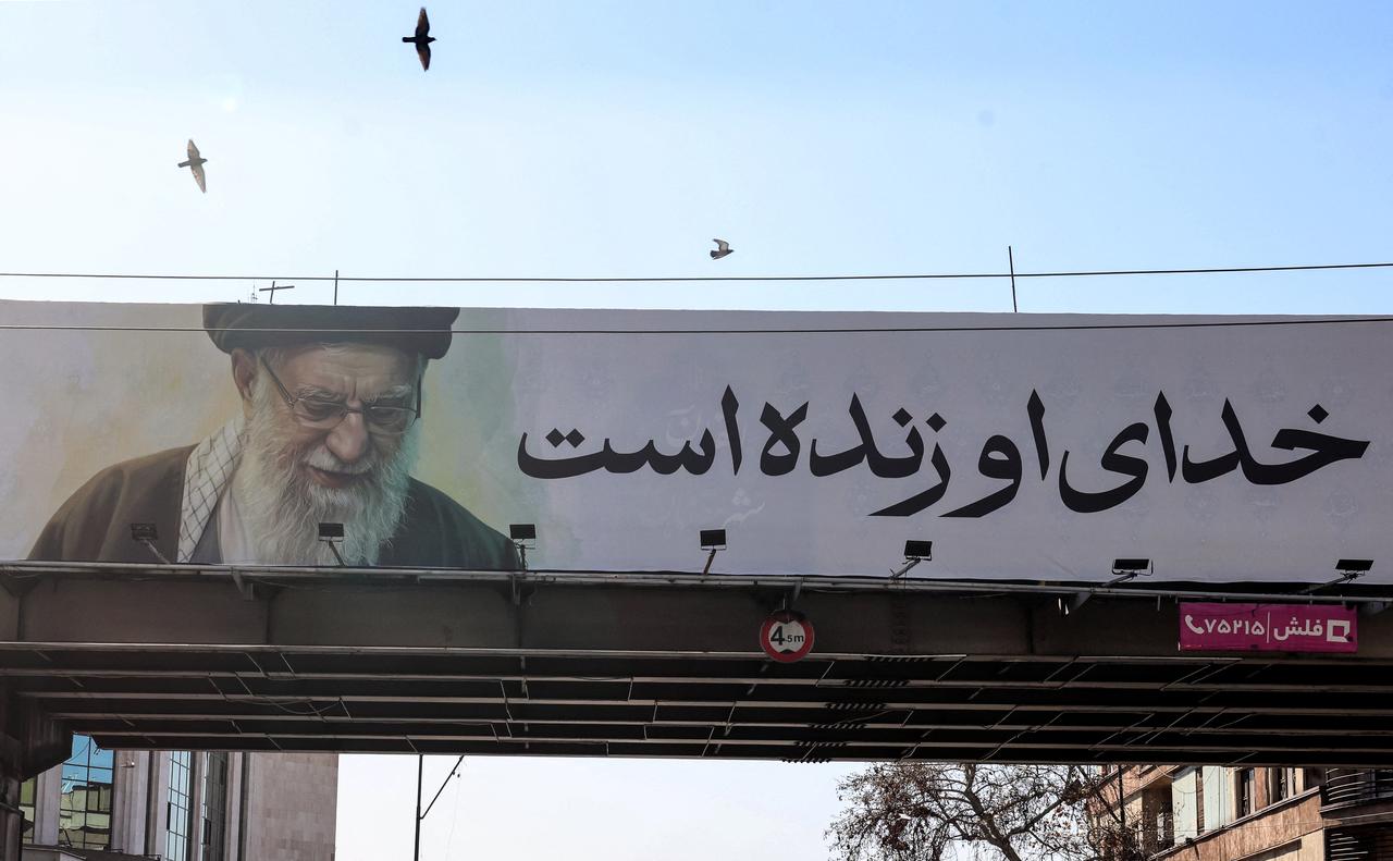 This photograph shows a banner bearing a portrait of Iran's slain supreme leader Ali Khamenei and reading in Persian "His God is still alive" in Tehran, March 3, 2026. (AFP Photo)