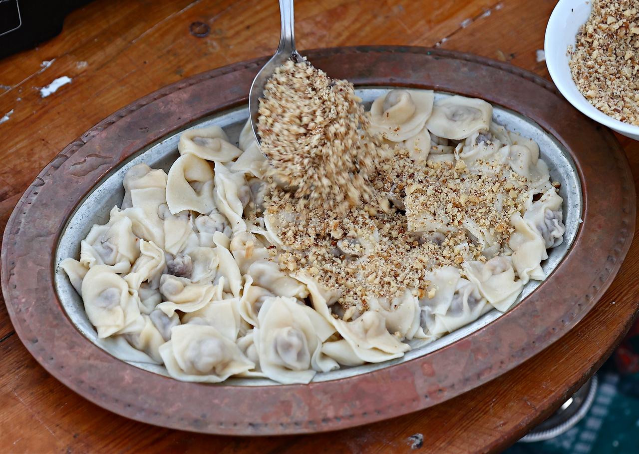 Finely ground walnuts are sprinkled over freshly cooked Sinop mantisi before serving in Sinop, Türkiye, March 6, 2026. (AA Photo)