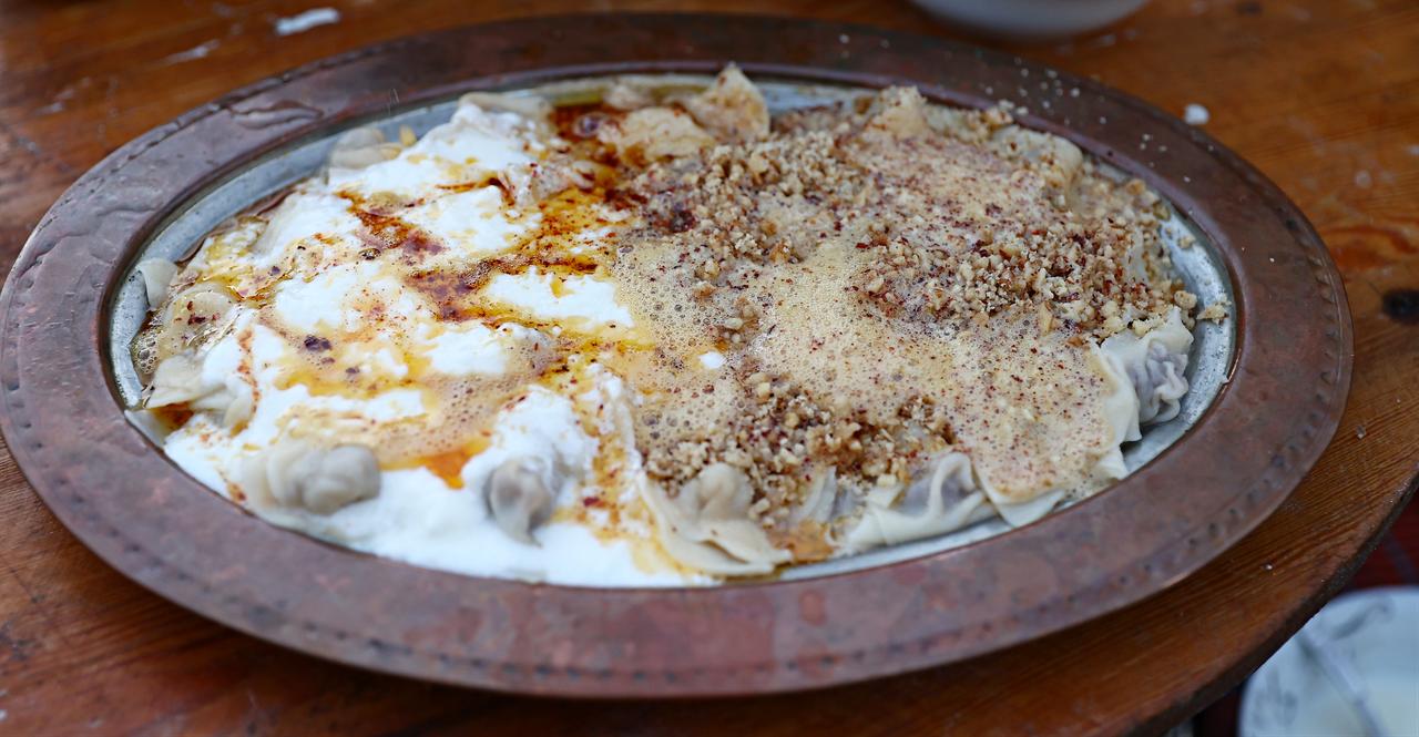 Sinop mantisi is served with yogurt, red pepper flakes and crushed walnuts on a traditional copper tray in Sinop, Türkiye, March 6, 2026. (AA Photo)