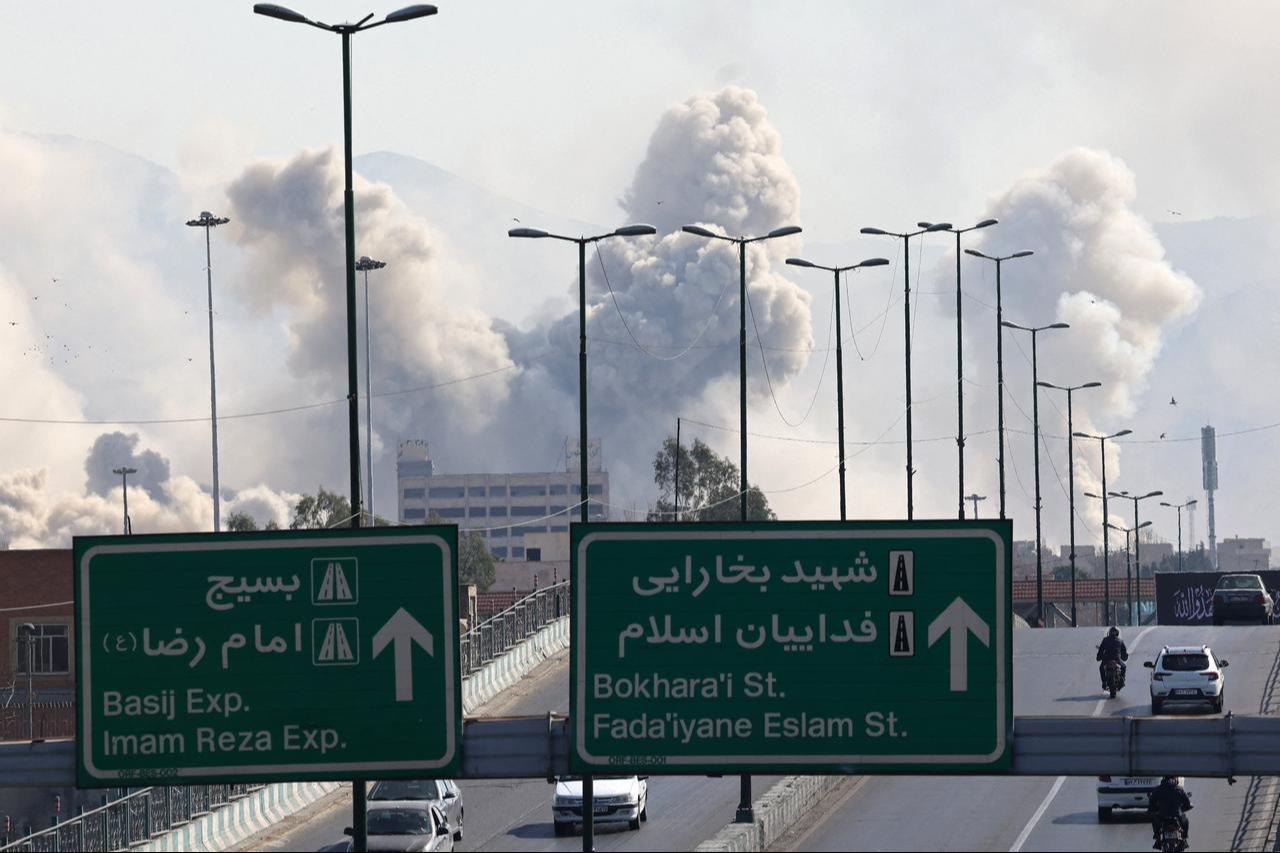 Vehicles drive along an expressway against the backdrop of smoke rising after a strike on the Iranian capital of Tehran on March 5, 2026. (AFP Photo)