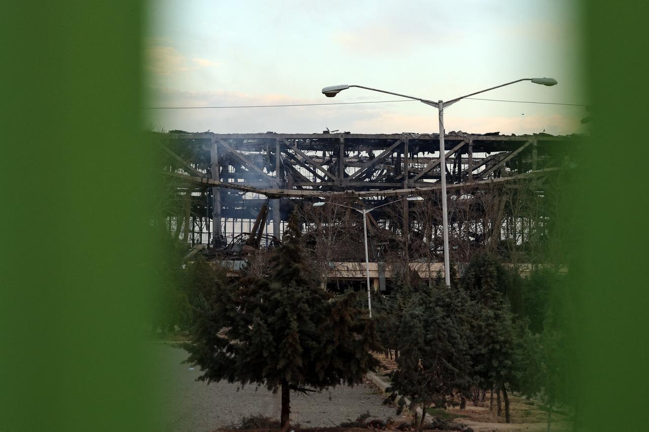 A photograph taken through a fence shows a heavily damaged building at Tehran's Azadi Sport Complex following a strike, on March 5, 2026. (AFP Photo)