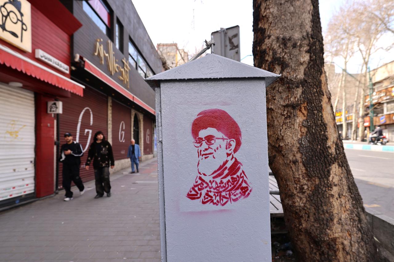 Iranians walk past shuttered shops and an image of Iran’s slain supreme leader Ali Khamenei (R) along a street near Tajrish Square in Tehran, on March 7, 2026. (AFP Photo)