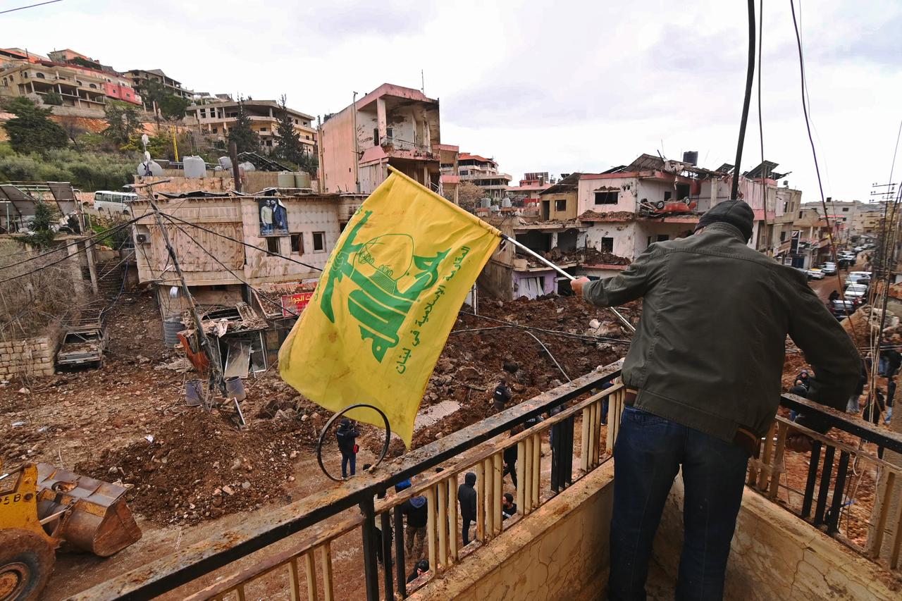 A man installing a flag of Hezbollah on the balcony of a damaged building at Nabi Sheet town after an Israeli military operation in the Bekaa Valley of Lebanon, March 7, 2026. (AFP Photo)