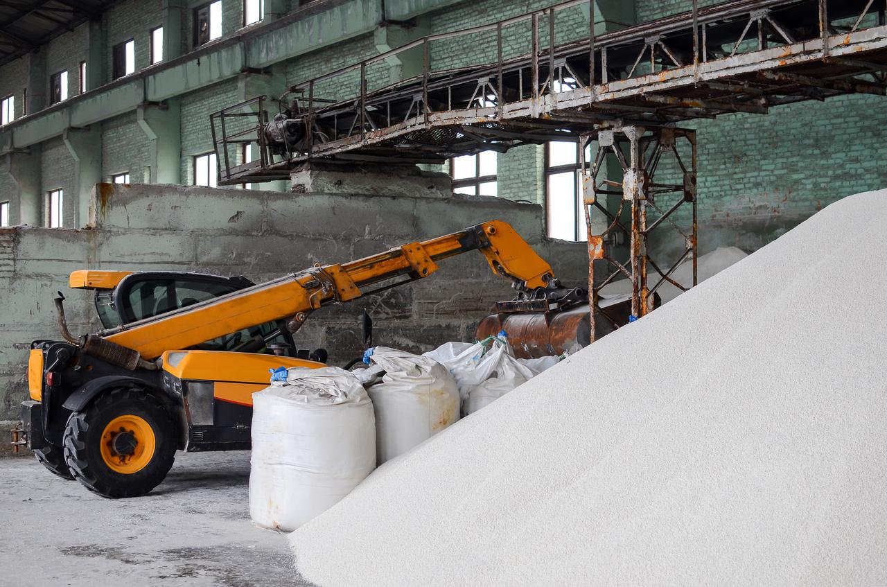 A loader moving urea fertilizer inside an industrial storage facility. (Adobe Stock Photo)