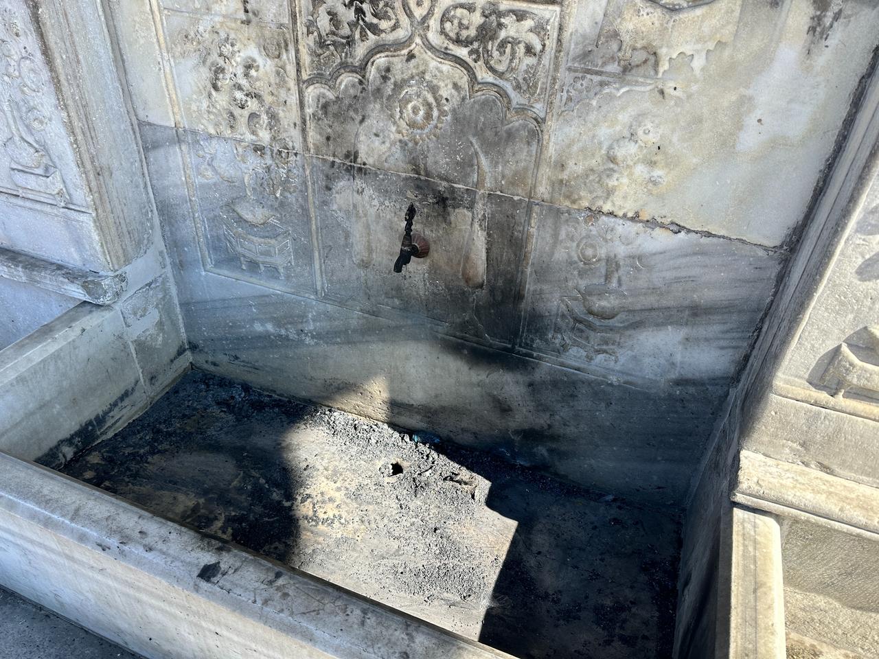 Soot and burn marks cover the marble basin of the historic Tophane Fountain after a fire was lit inside the structure overnight in Istanbul, Türkiye, March 8, 2026. (AA Photo)
