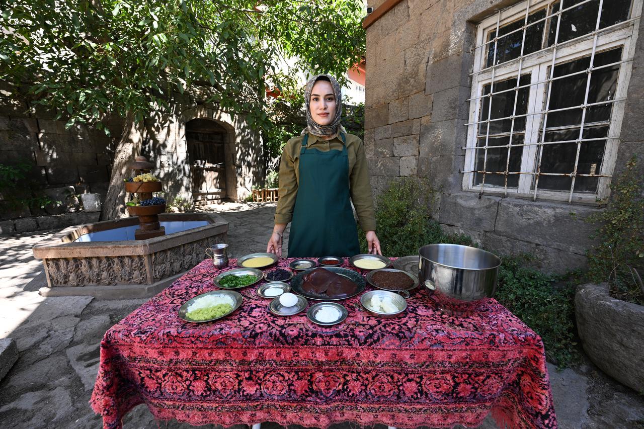 Busra Sunav Tek prepares ingredients for the traditional Bitlis dish ciger taplamasi in a historic mansion courtyard in Bitlis, Türkiye, March 9, 2026. (AA Photo)