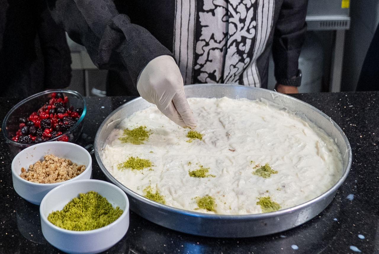 Indonesian Ambassador to Ankara Achmad Rizal Purnama sprinkles pistachios over a tray of gullac, a traditional Turkish Ramadan dessert, in Ankara, Türkiye, March 8, 2026. (AA Photo)