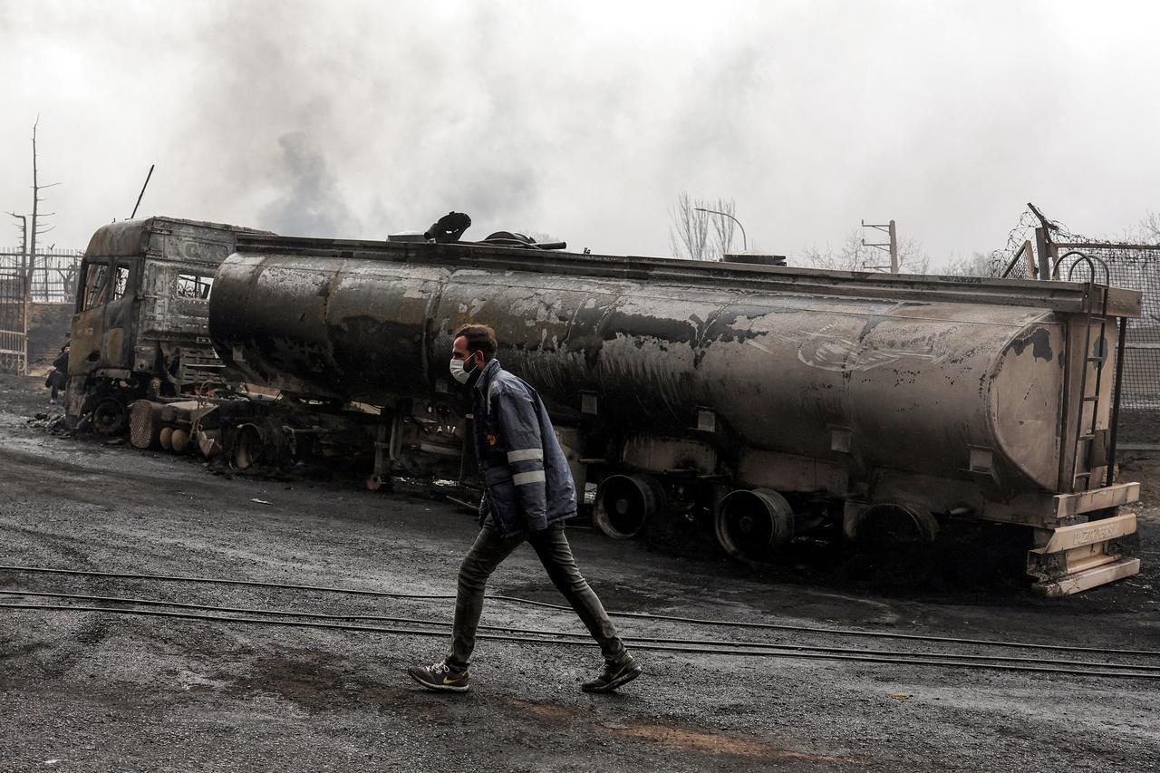 An Iranian civil defence member walks next to a destroyed fuel tanker vehicle near an ongoing fire following an overnight airstrike on the Shahran oil refinery in northwestern Tehran, March 8, 2026. (AFP Photo)