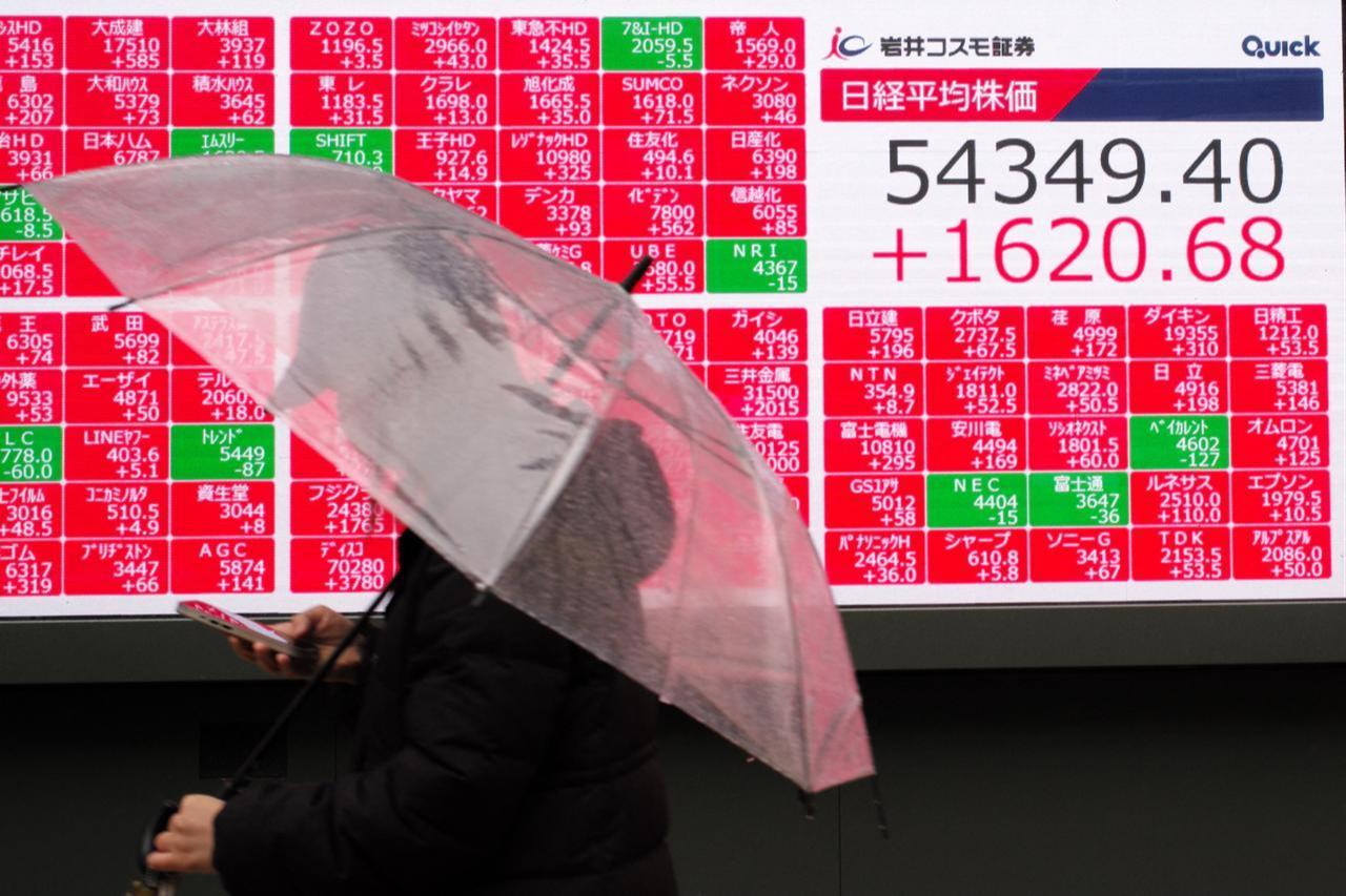 A man walks in front of an electronic quotation board displaying the Nikkei Stock Average on the Tokyo Stock Exchange along a street in Tokyo, March 10, 2026. (AFP Photo)