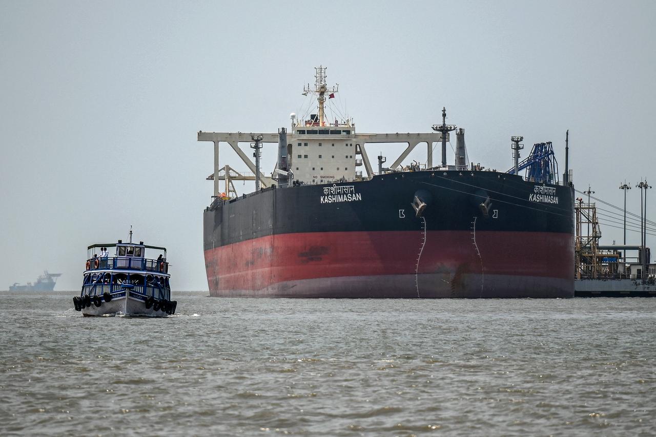 A passenger boat sails past an Indian-flagged oil tanker, Kashimasan, docked near an offloading terminal at Butcher Island, off the coast of Mumbai, April 1, 2026. (AFP Photo)