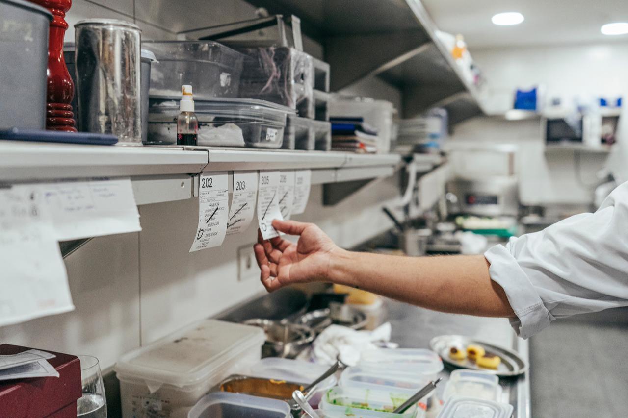 A chef organizes digital food delivery orders inside a ghost kitchen, where meals are prepared exclusively for online customers. (Adobe Stock Photo)