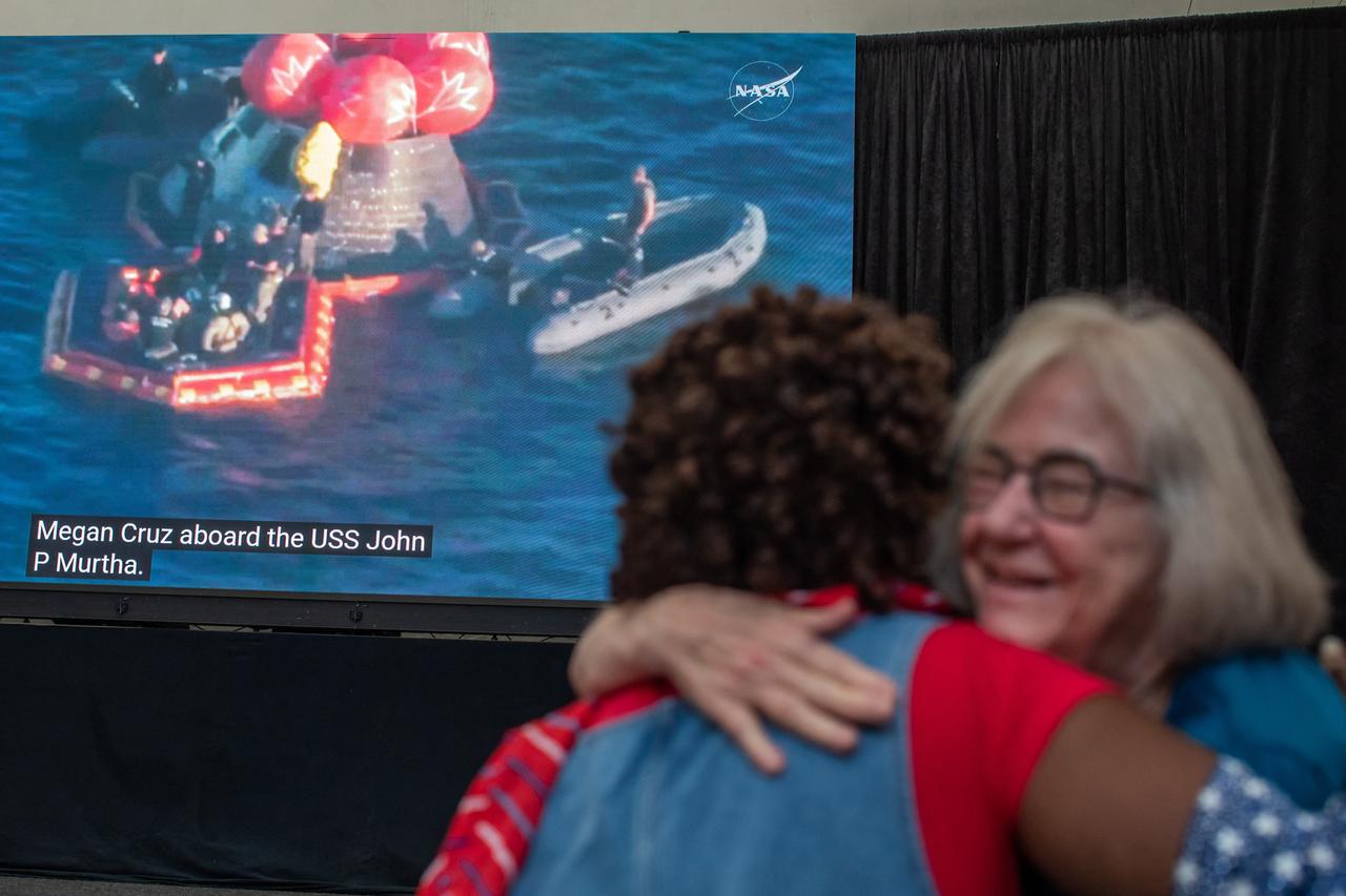 People hug as they watch a live broadcast of the return of the Artemis II crew members to Earth at the San Diego Air and Space Museum during a watch party for the crew's splash down in the Pacific Ocean, in San Diego, California, on April 10, 2026. (AFP Photo)