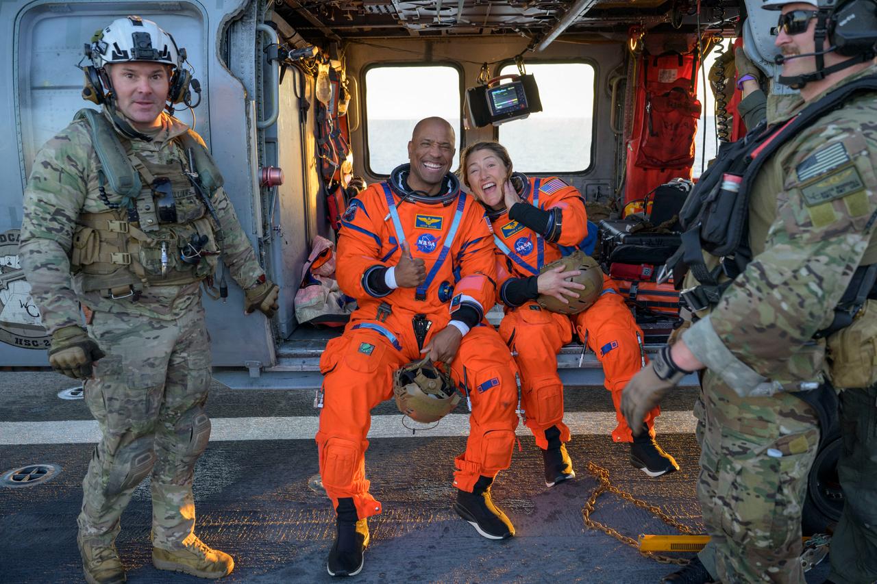This handout photo released by NASA shows NASA astronaut Victor Glover (L) and Christina Koch sitting on a Navy MH-60 Seahawk from Helicopter Sea Combat Squadron 23 on the flight deck of USS John P. Murtha in the Pacific Ocean off the coast of California, on April 10, 2026.