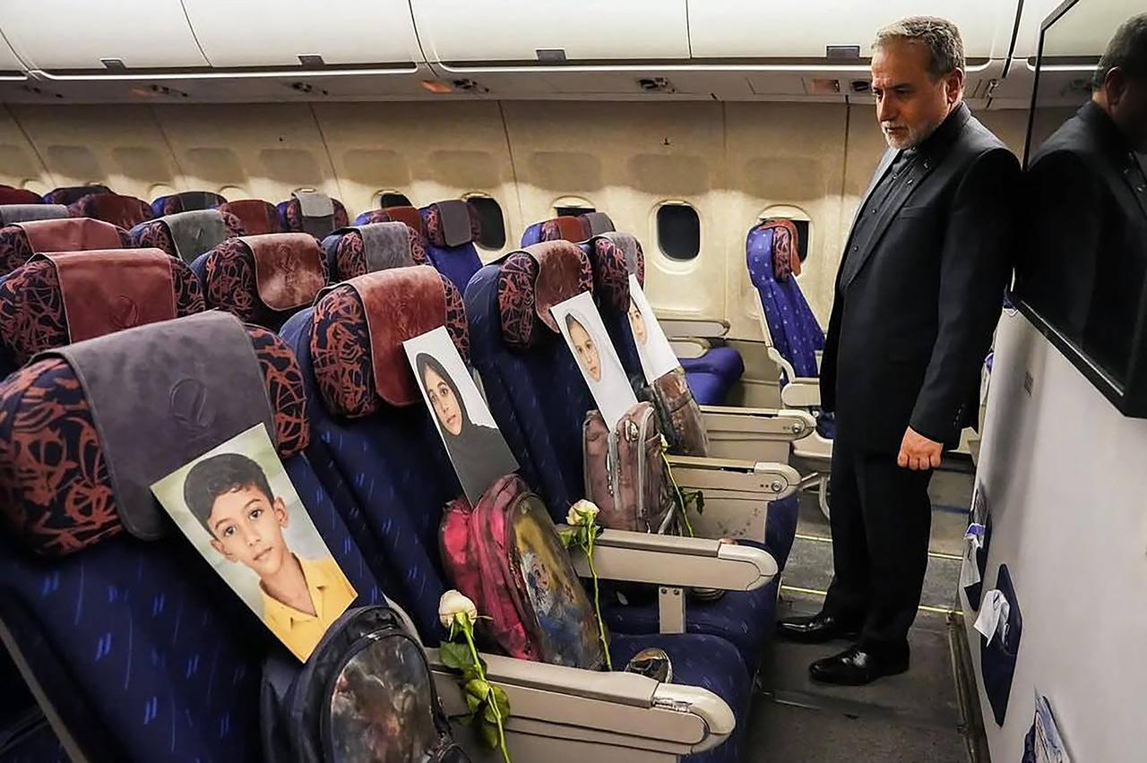 Iran's Foreign Minister Abbas Araghchi looking at the photos of the children killed in Madrasa Minab in Iran, while aboard a plane on his way to Pakistan for talks with the United States. (Photo by Iranian Ministry of Foreign Affairs/AFP)