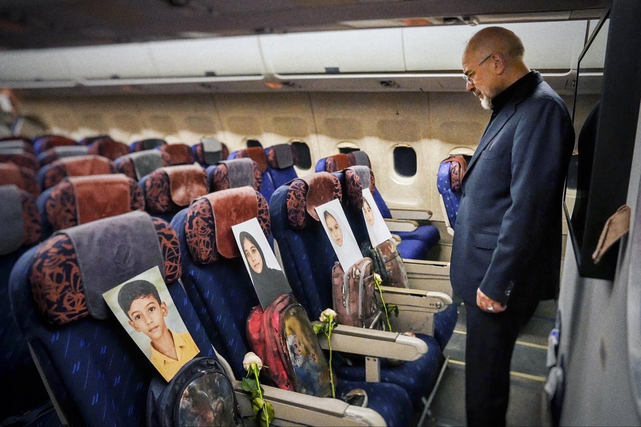 Iranian Parliament Speaker Mohammad Bagher Qalibaf looks at photographs and backpacks of children killed in U.S. and Israeli strikes on Minab, placed on seats aboard the plane en route to Islamabad, Pakistan, April 10, 2026. (AA Photo)