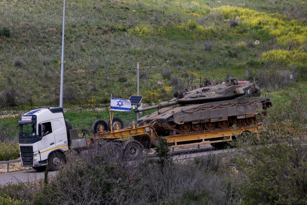 An Israeli military truck carries a tank in the Upper Galilee region of northern Israel, near the border with Lebanon on March 31, 2026. (AFP Photo)