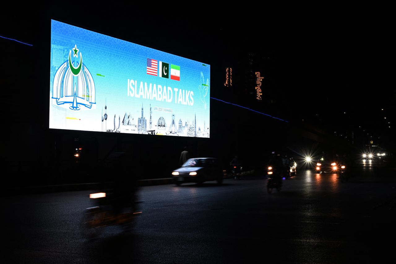 Commuters ride past a digital screen as the US and Iran hold peace talks in Islamabad on April 11, 2026. (AFP Photo)