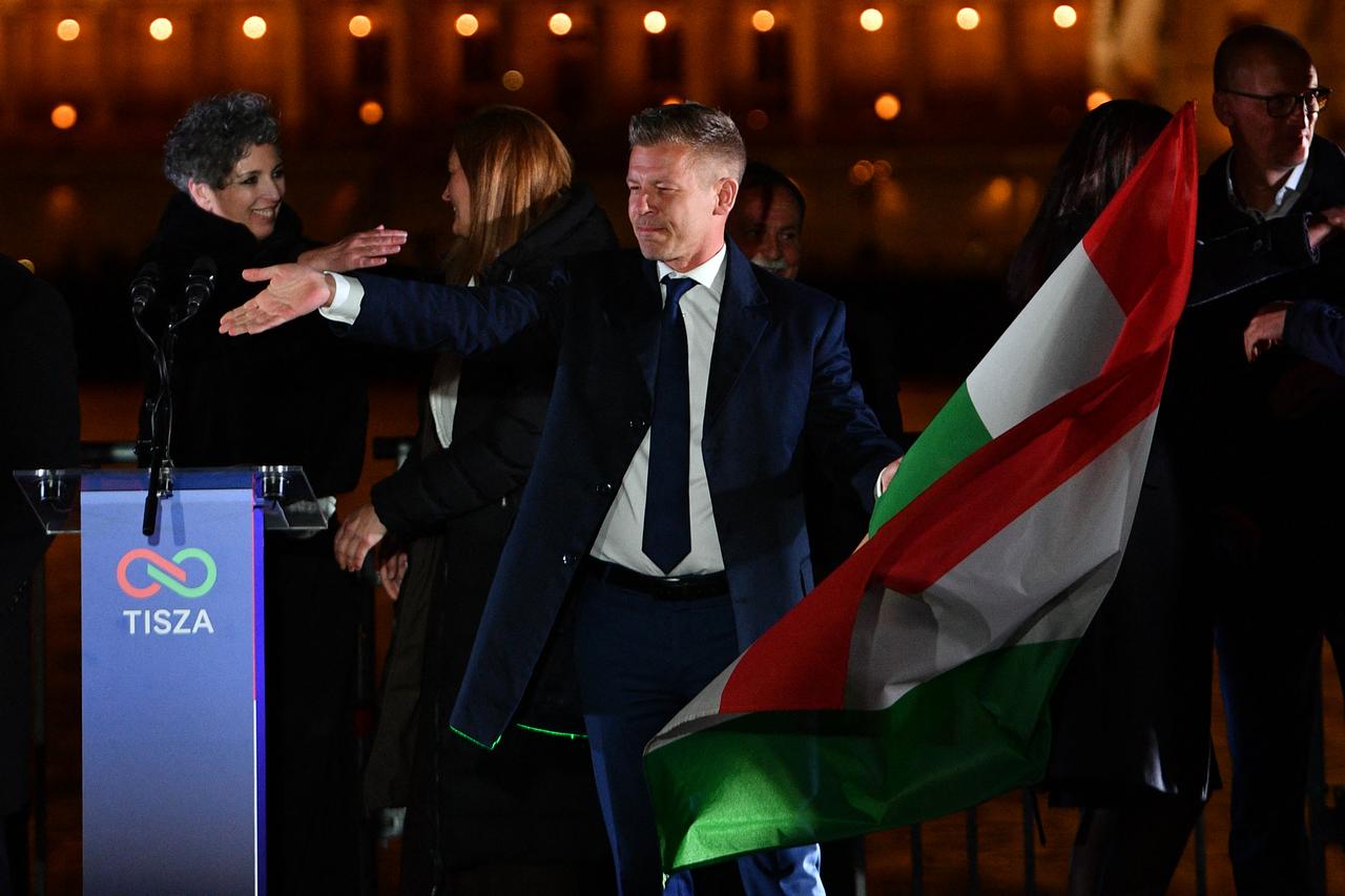 Peter Magyar, leader of the pro-European conservative TISZA party, waves the national flag on the banks on the river Danube with the Parliament building in the background, during their election night party in Budapest during the general election in Hungary, on April 12, 2026. (AFP Photo)