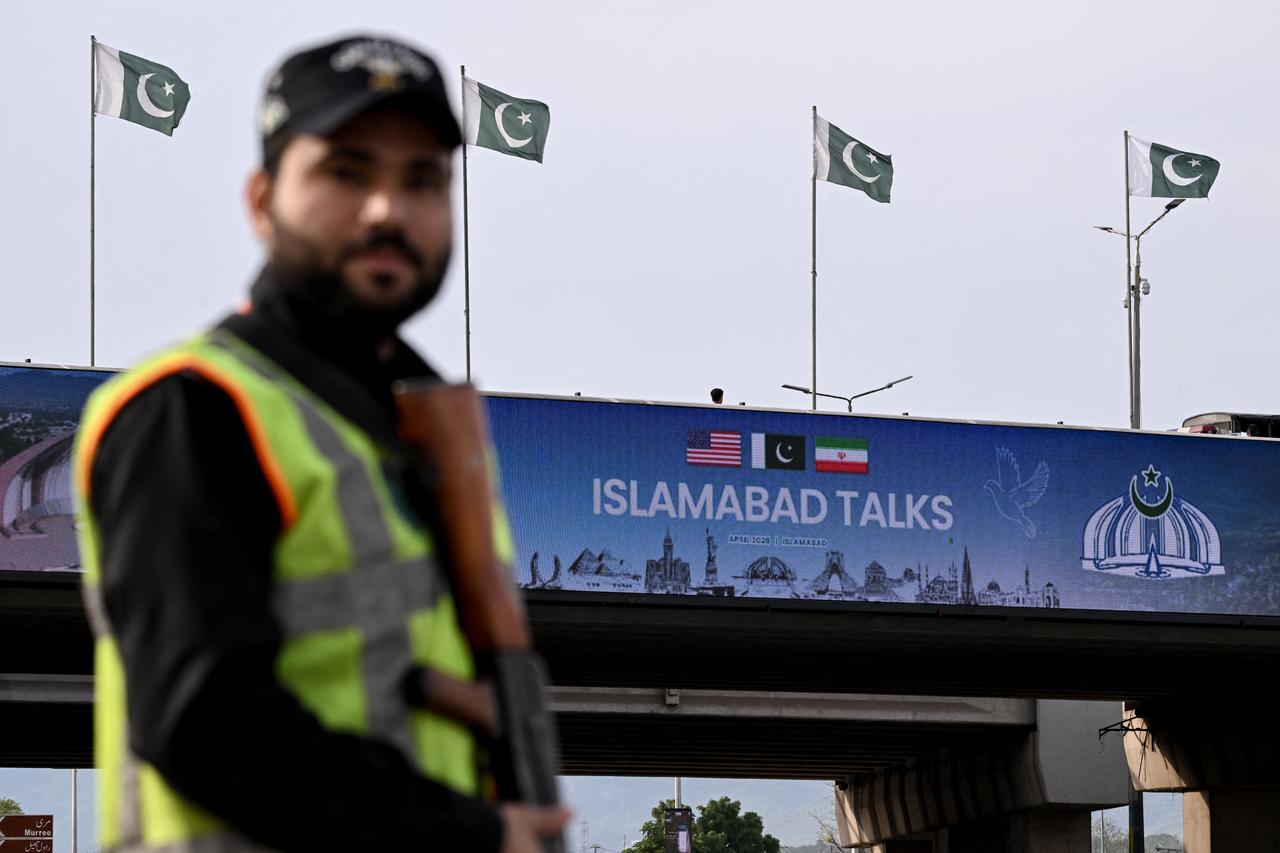 A policeman stands guard in front of a digital screen displaying news of US–Iran peace talks along a road in Islamabad, April 10, 2026. (AFP Photo)