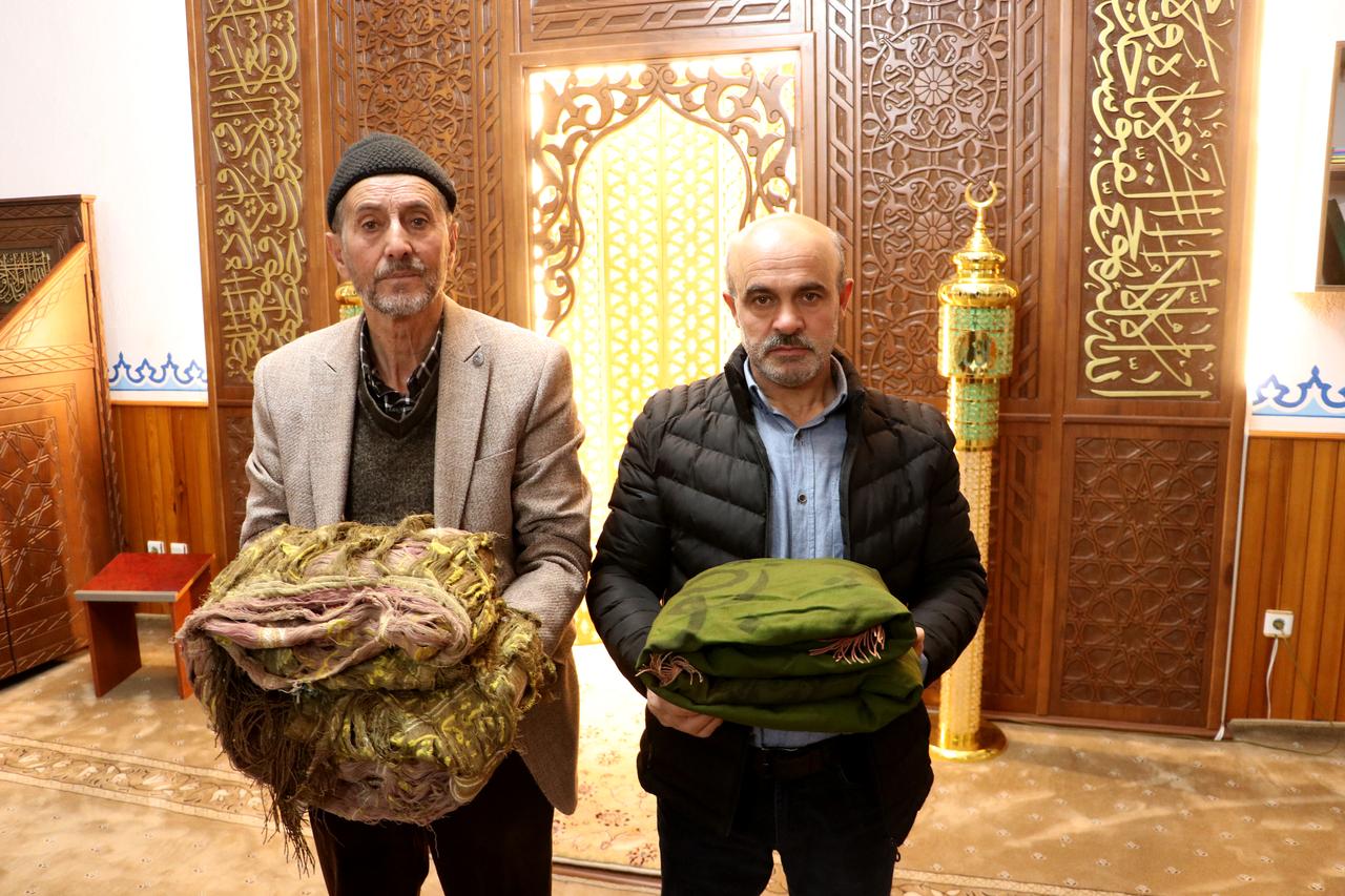 Two men hold folded historic banners dating back to the Eretna Beylik and Ottoman period inside a mosque in Kayseri, Türkiye. (AA Photo)