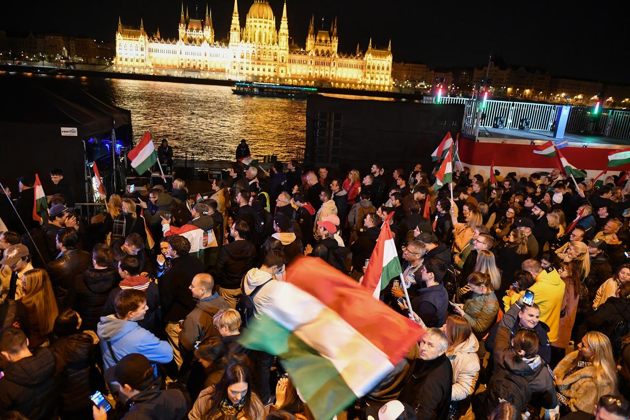 Supporters of Peter Magyar, leader of the pro-European conservative TISZA party, celebrate on the banks on the river Danube with the Parliament building in th ebackground in Budapest during the general election in Hungary, on April 12, 2026. (AFP Photo)