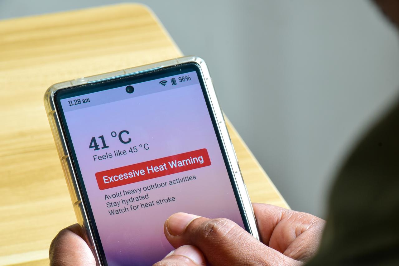A man looks at a mobile phone displaying an excessive heat warning in an undated Adobe Stock photo. (Adobe Stock Photo)