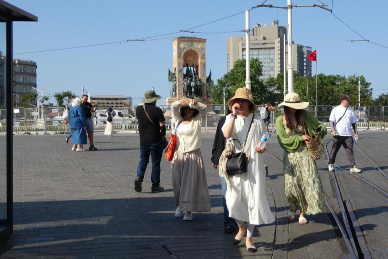 Tourists seek shade from the sun as they walk through Taksim Square in Istanbul, Türkiye, amid sweltering heat, June 18, 2025. (IHA Photo)