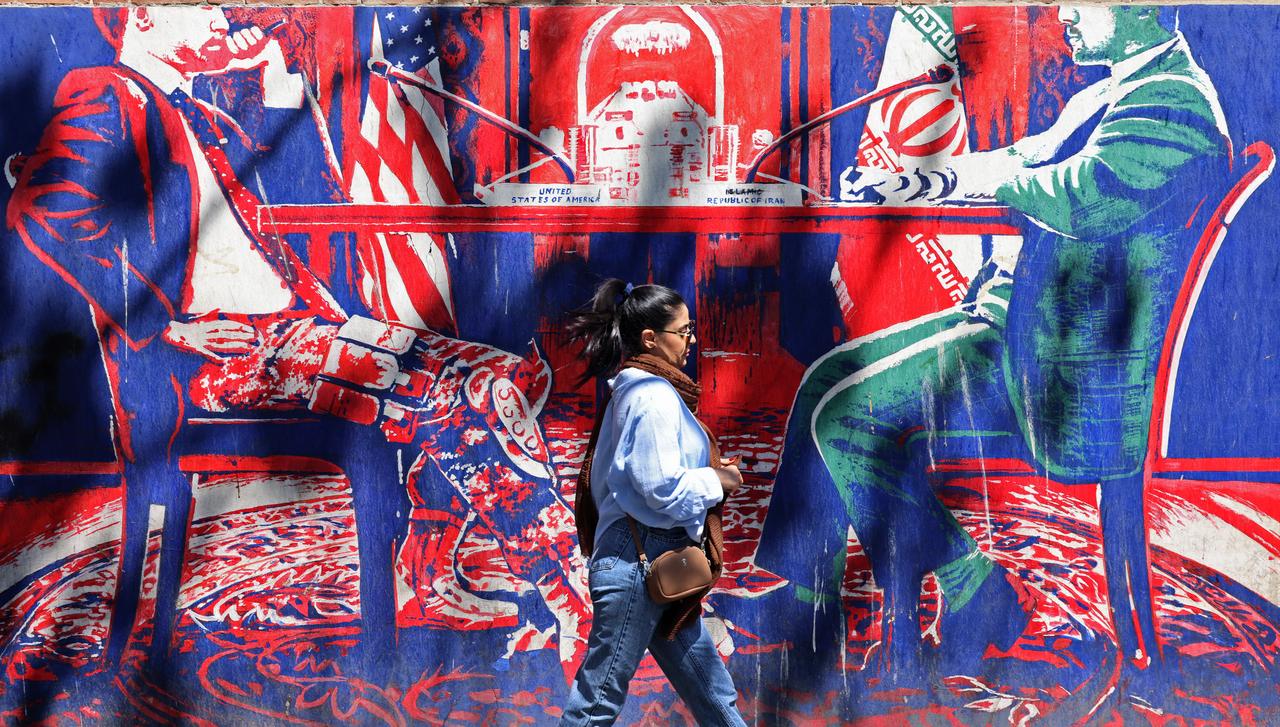 A woman walks past an anti-US mural depicting Iran-US talks near the former US embassy in Tehran on April 11, 2026. (AFP Photo)