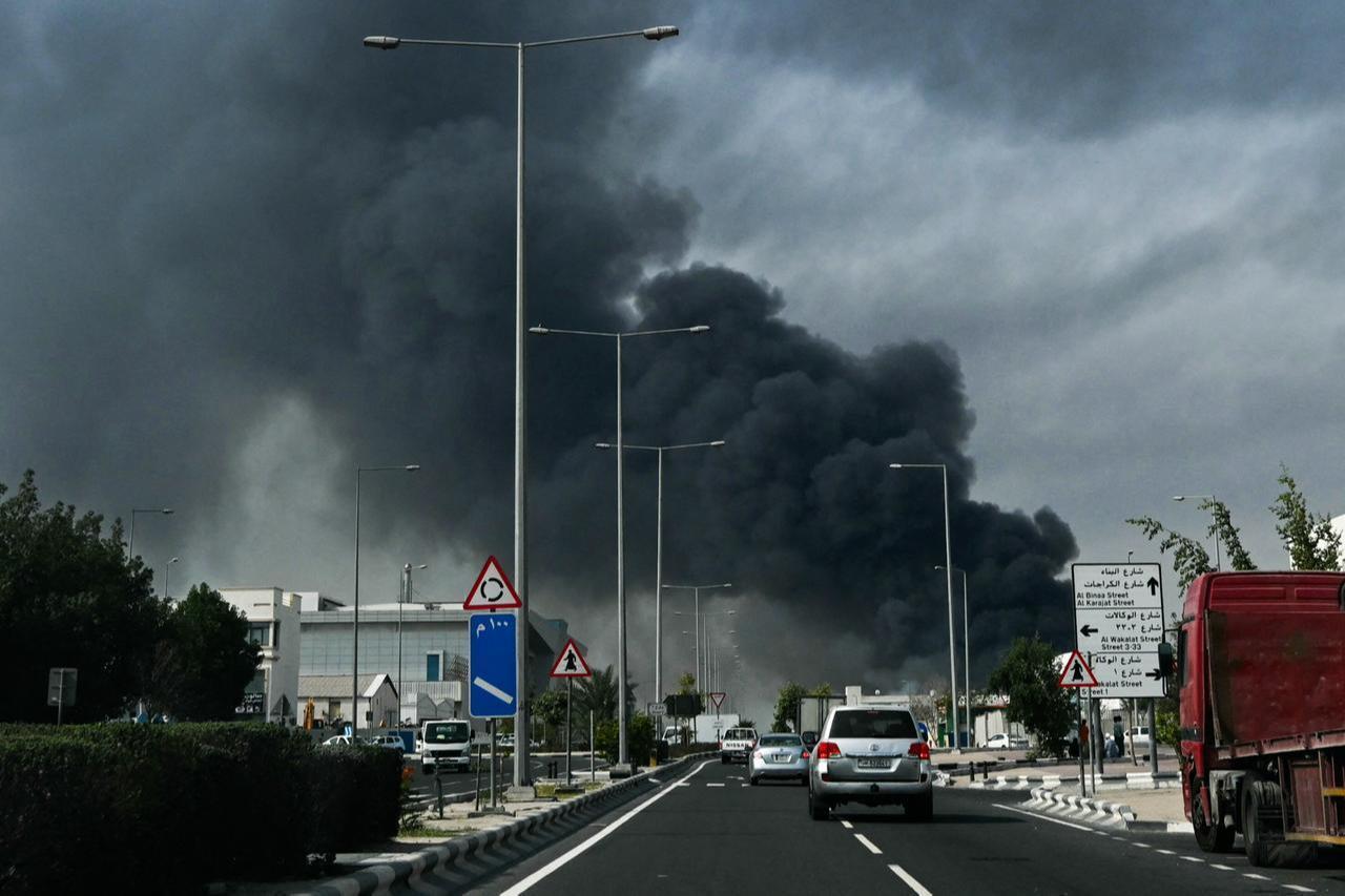 Motorists drive past a plume of smoke rising from a reported Iranian strike in the industrial district of Doha on March 1, 2026. (AFP Photo)