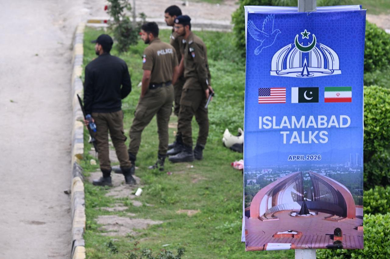 Policemen stand beside a poster on a street referencing the US–Iran peace talks in Islamabad on April 11, 2026. (AFP Photo)