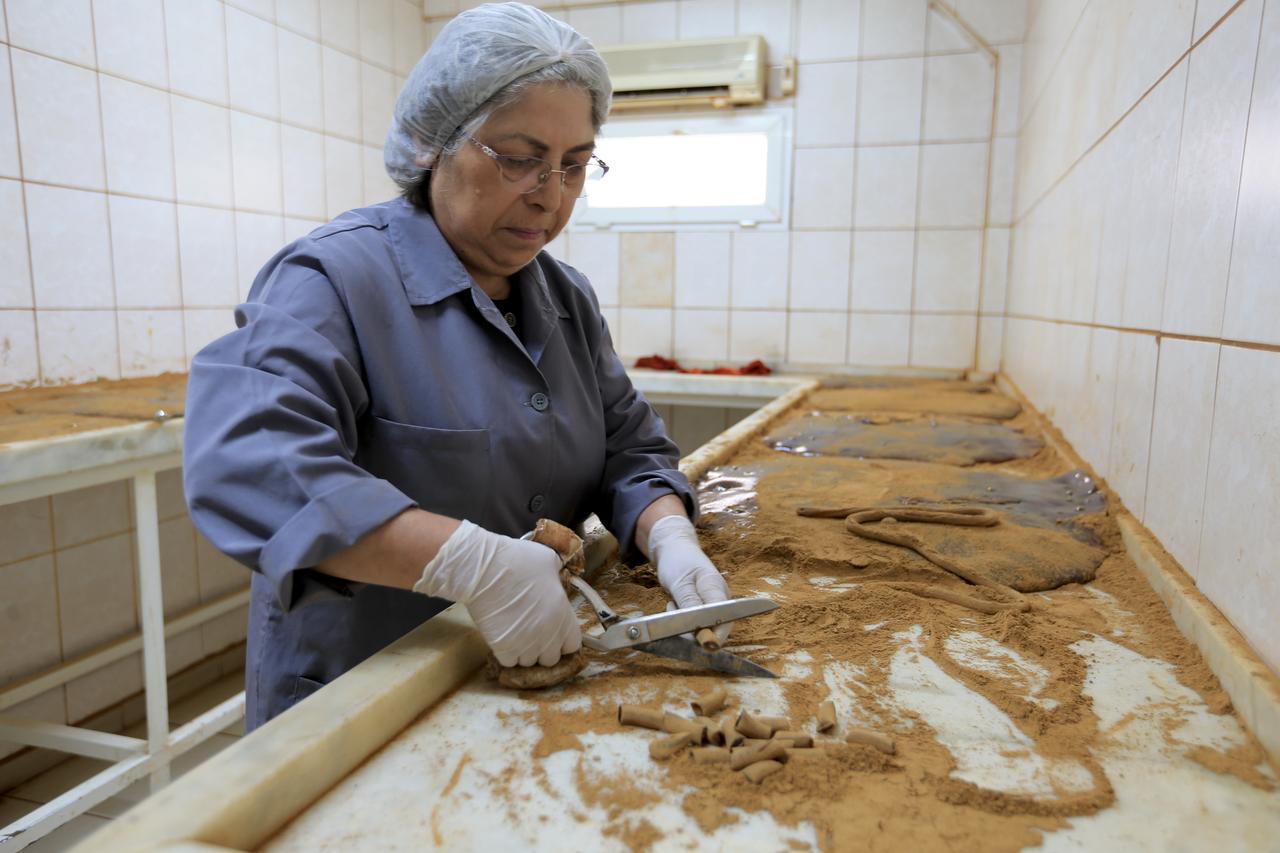 A worker uses large scissors to manually cut the spiced paste into traditional cylindrical shapes, Manisa, Türkiye, April 14, 2026. (AA Photo)