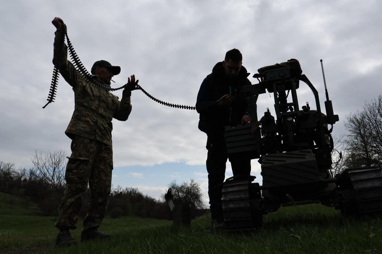 In this handout photograph taken and released by the press service of the 65th Mechanized Brigade of Ukrainian Armed Forces on April 10, 2026, Ukrainian servicemen load ammunition into a machine gun mounted on a combat ground drone during a training at an undisclosed location in Zaporizhzhia region, amid the Russian invasion of Ukraine. (65th Mechanized Brigade of Ukrainian Armed Forces / AFP Photo)