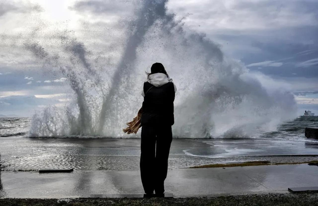 Waves crash over the shoreline during a powerful storm, sending sea spray high into the air as a person stands facing the rough waters in Istanbul, Türkiye. (IHA Photo)