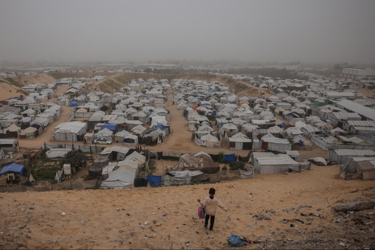 A child walks down a hill overlooking a camp for displaced Palestinians during hazy and dusty weather in Khan Yunis, in the southern Gaza Strip, on February 14, 2026. (AFP Photo)