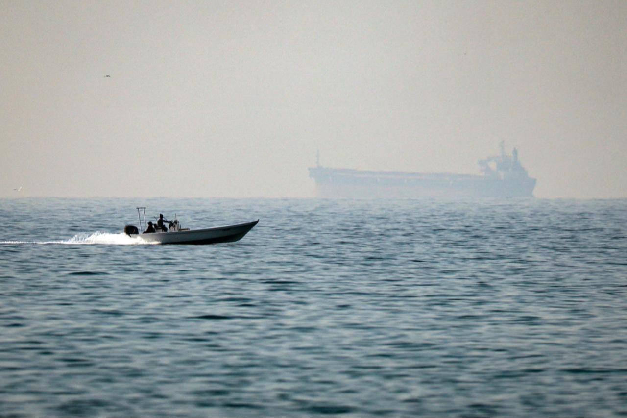 A motorboat cruises along the shore off the town of Al Jeer on the Strait of Hormuz in the northern emirate of Ras Al Khaimah, with a tanker seen in the background, Feb. 25, 2026. (AFP Photo)
