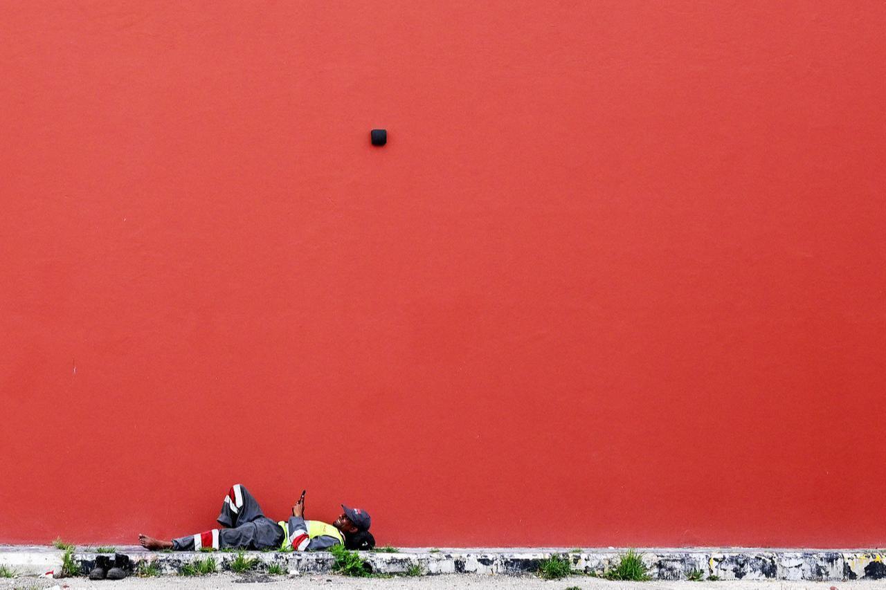 A sanitation worker rests in the shade of a building near an unofficial camp for displaced people in Beirut's waterfront area on April 14, 2026. (AFP Photo)
