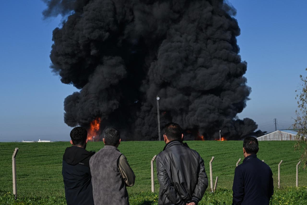 People watch as smoke billows from an oil warehouse in the Kani Qirzhala area on the outskirts of Erbil following a suspected drone strike, April 1, 2026. (AFP Photo)