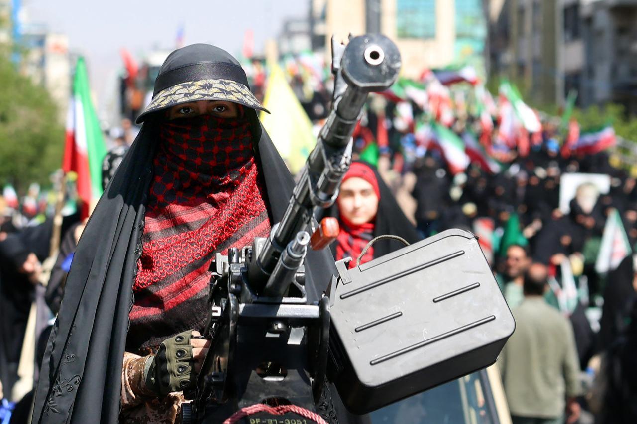 An Iranian woman stands at a heavy machine gun mounted on the back of a vehicle as she takes part in a rally in Tehran on April 17, 2026. (AFP Photo)