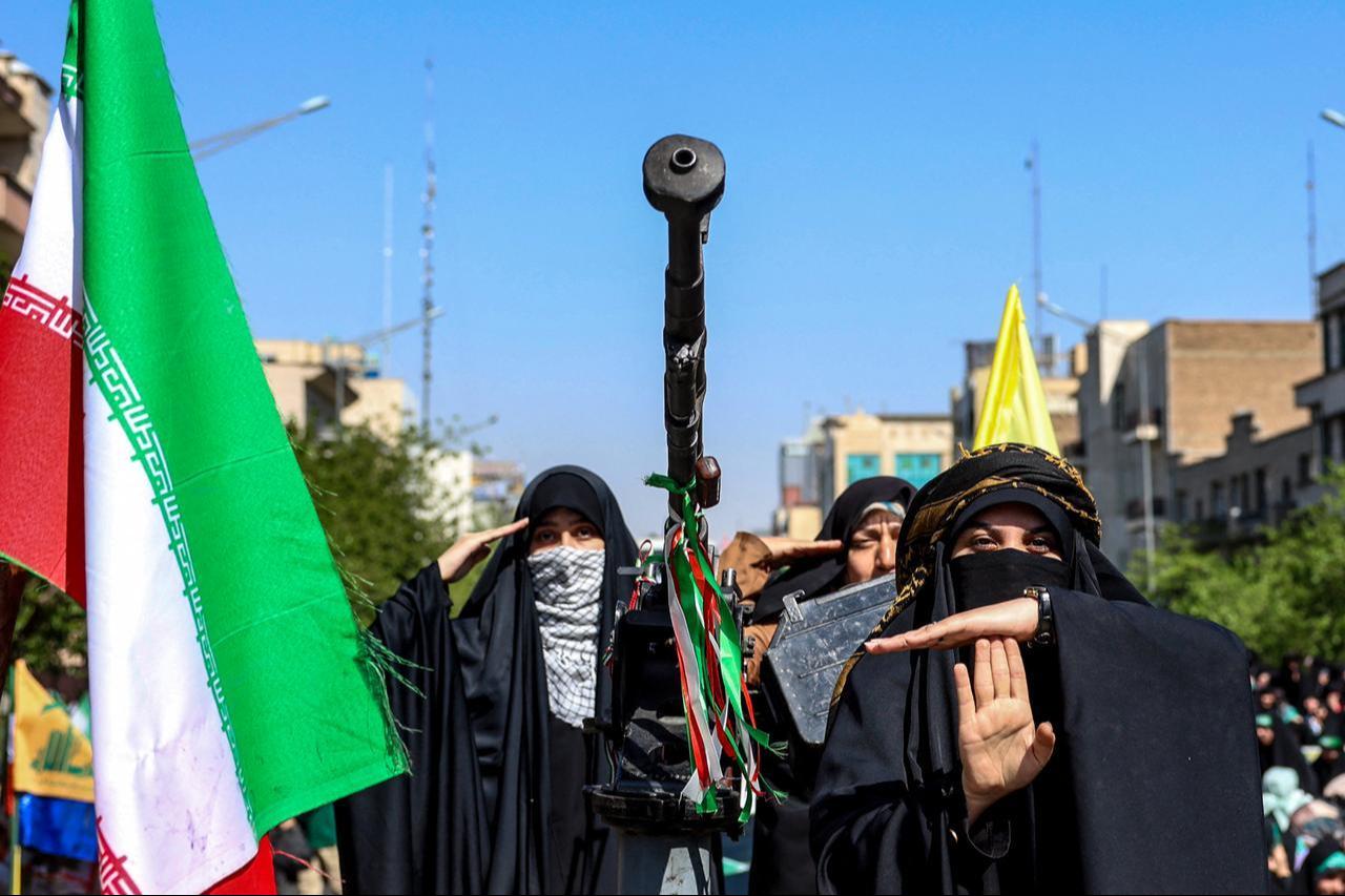 Iranian women stand beside a heavy machine gun as they ride in the back of a vehicle during a rally in Tehran, Iran on April 17, 2026. (AFP Photo)