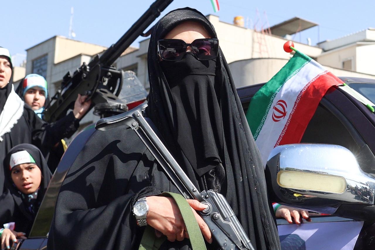 An Iranian woman brandishes a rifle during a rally in Tehran on April 17, 2026. (AFP Photo)