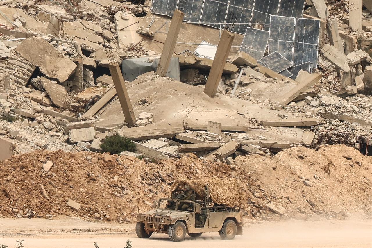 A photograph taken from the Israeli side of the border with Lebanon shows Israeli soldiers driving along a road running beside destroyed buildings in southern Lebanon on April 15, 2026. (AFP Photo)