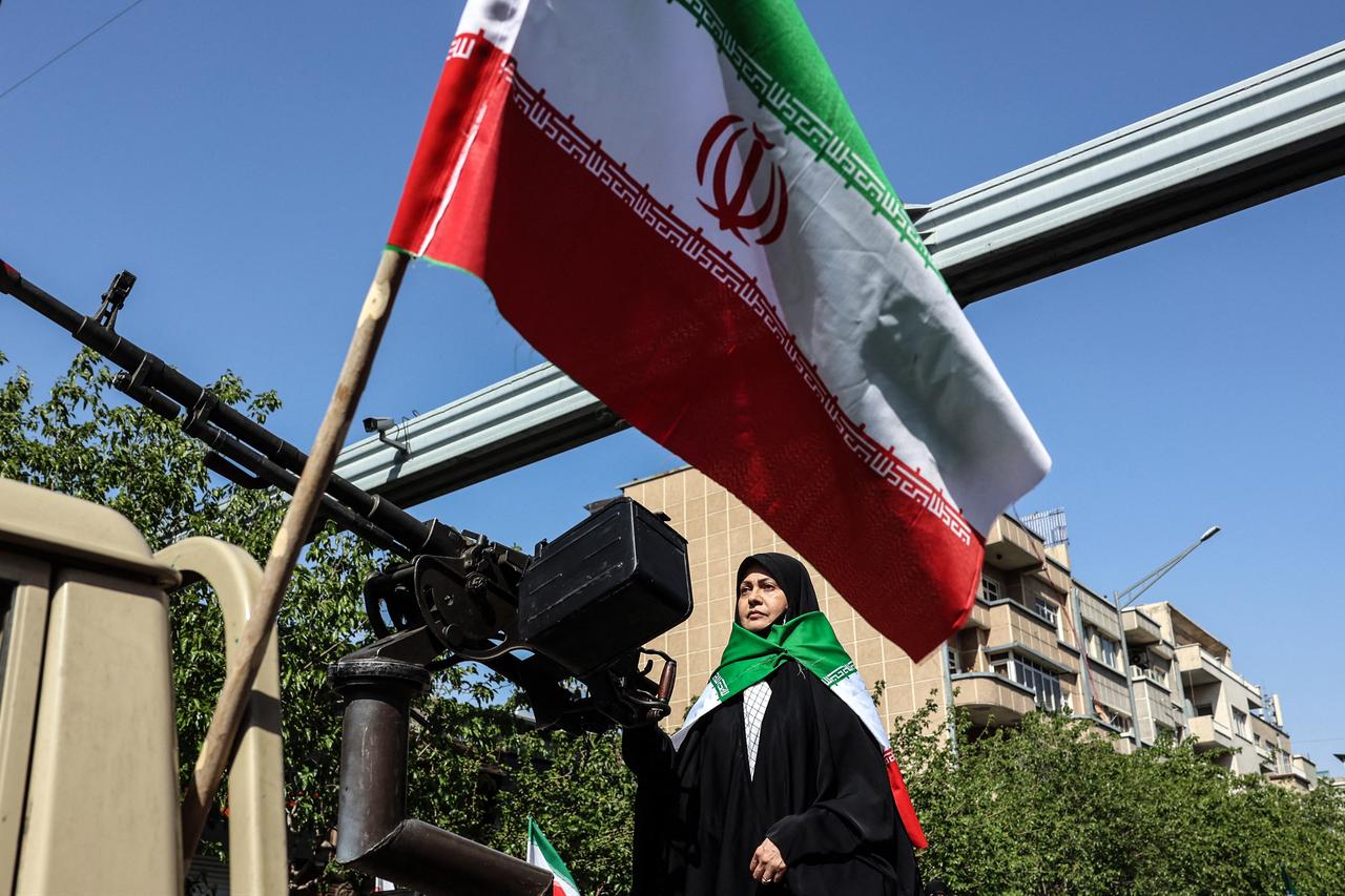 An Iranian woman stands at a heavy machine gun mounted on the back of a vehicle as she takes part in a rally in Tehran, April 17, 2026. (AFP Photo)