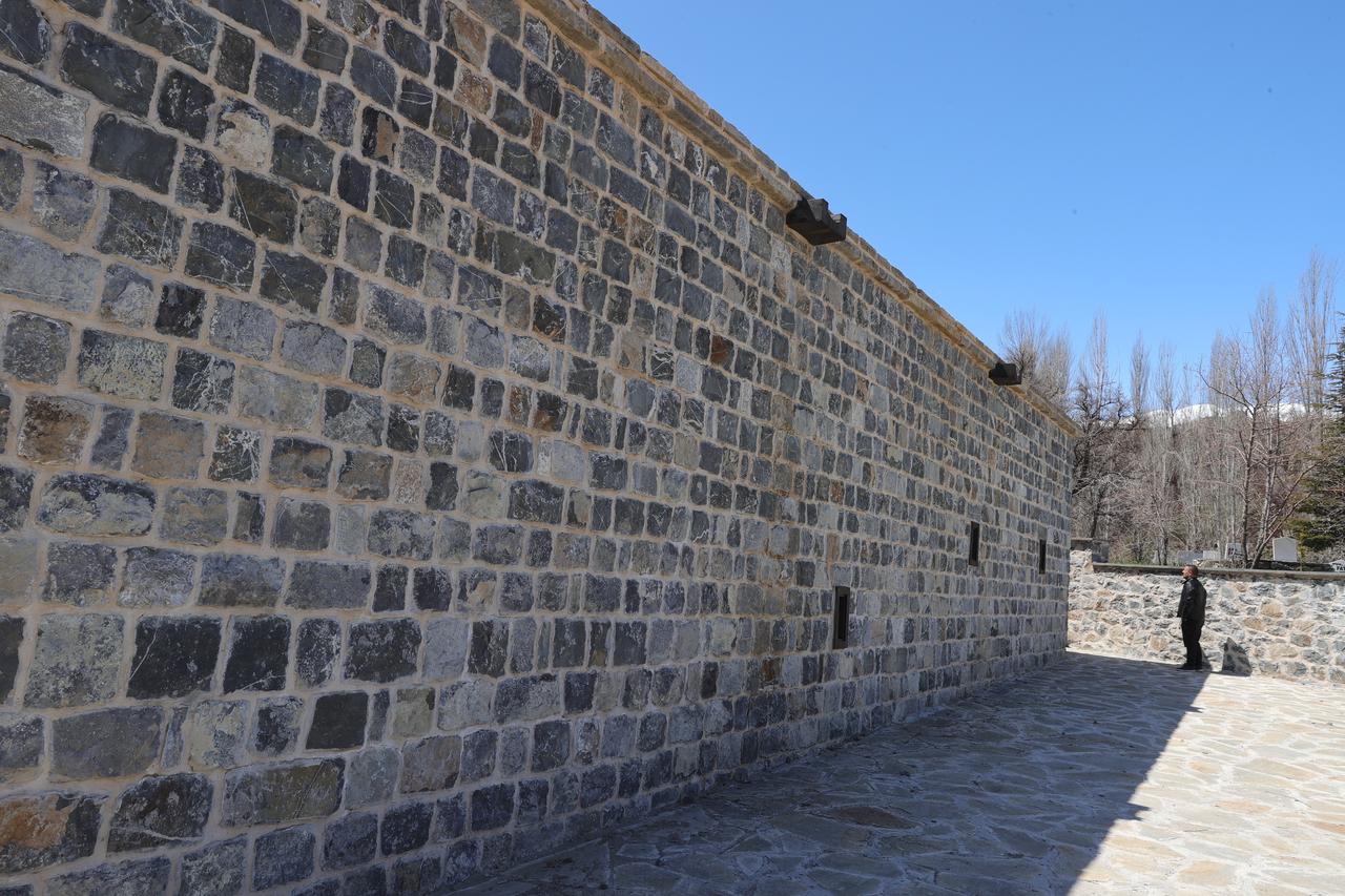 A visitor stands beside the long stone facade of Zeynel Bey Madrasa, highlighting its traditional architecture after restoration in Hakkari, Türkiye. (AA Photo)