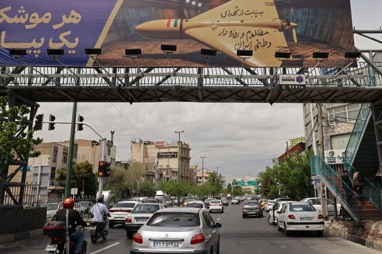 Motorists drive under a footbridge with a billboard reading in Persian "Every missile has a message" along a busy street in Tehran, April 19, 2026. (AFP Photo)